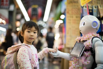 Ein kleines Mädchen, das mit einem Roboter Händchen hält